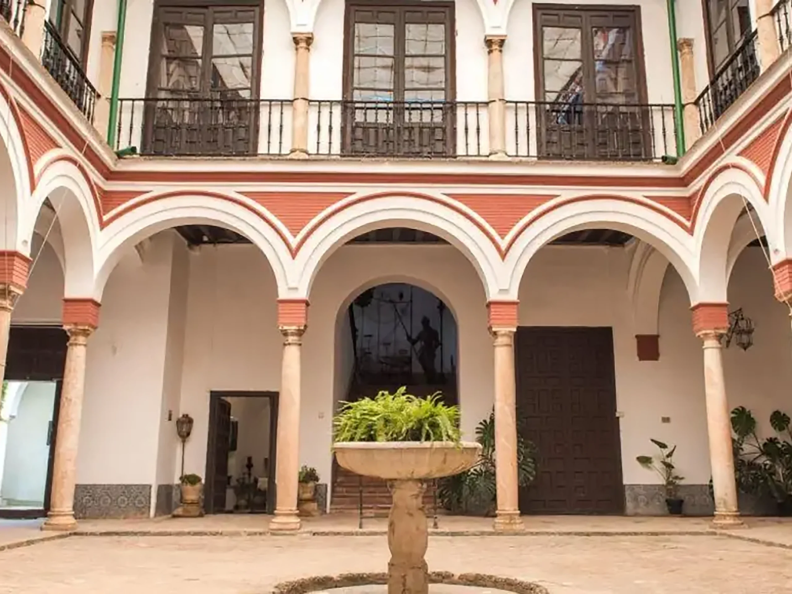 Patio y arcada del Palacio de los Bucarelli en Sevilla durante una visita cultural con Conoce Sevilla