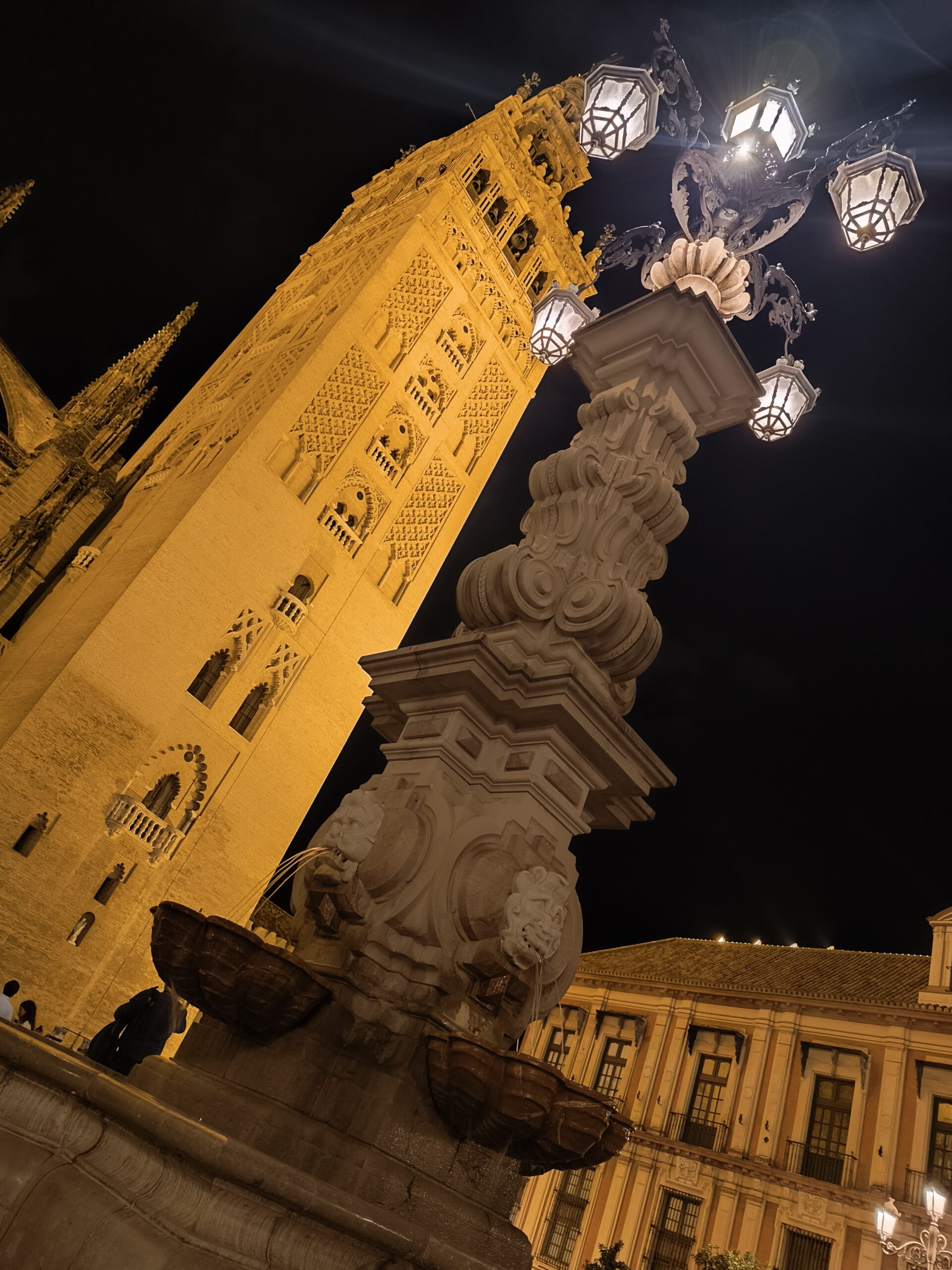 Giralda de Sevilla vista en diagonal desde la Plaza Virgen de los Reyes, con la farola de la fuente en primer plano, foto de Conoce Sevilla