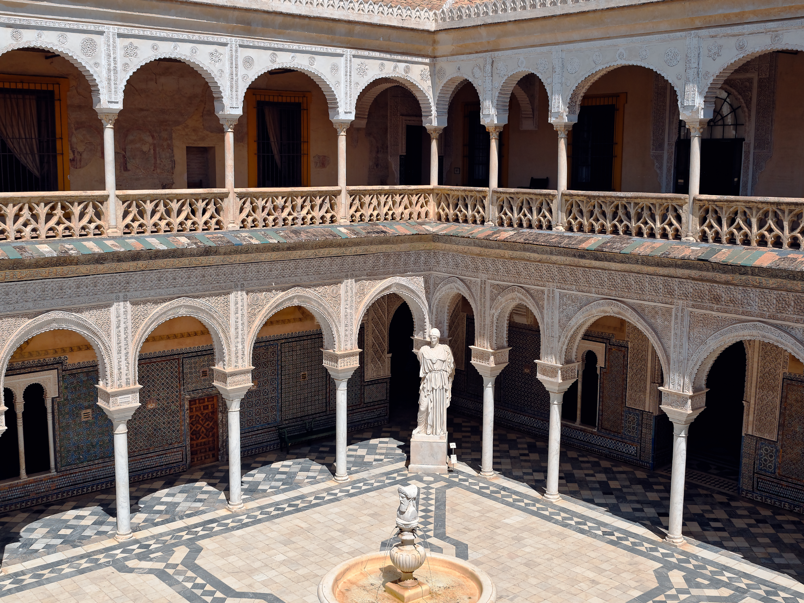 Patio de la Casa de Pilatos en Sevilla con la fuente central y una estatua en la esquina durante una visita cultural con Conoce Sevilla