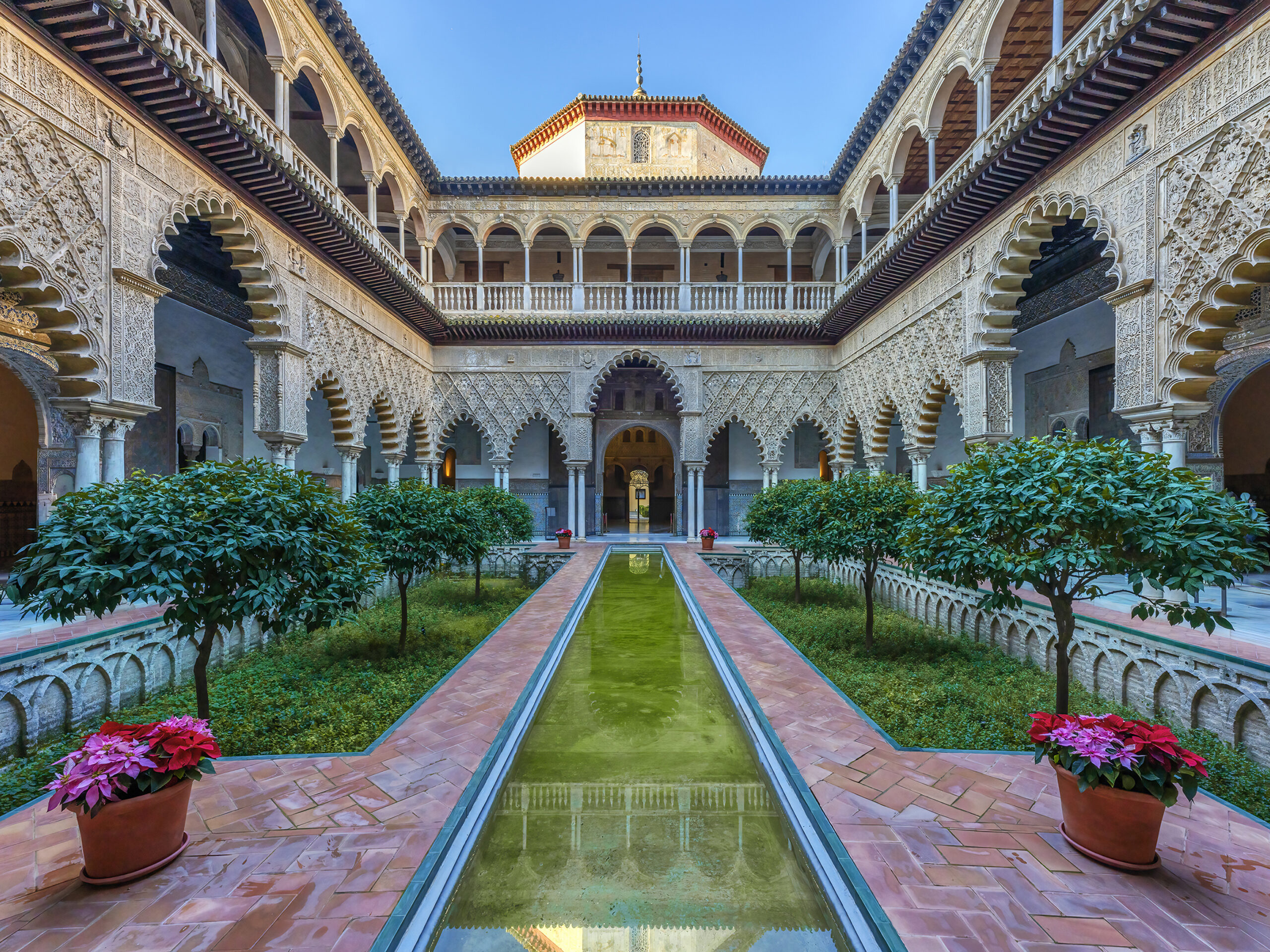 Patio del Alcázar de Sevilla visto a través de la fuente que lo recorre durante una visita cultural con Conoce Sevilla