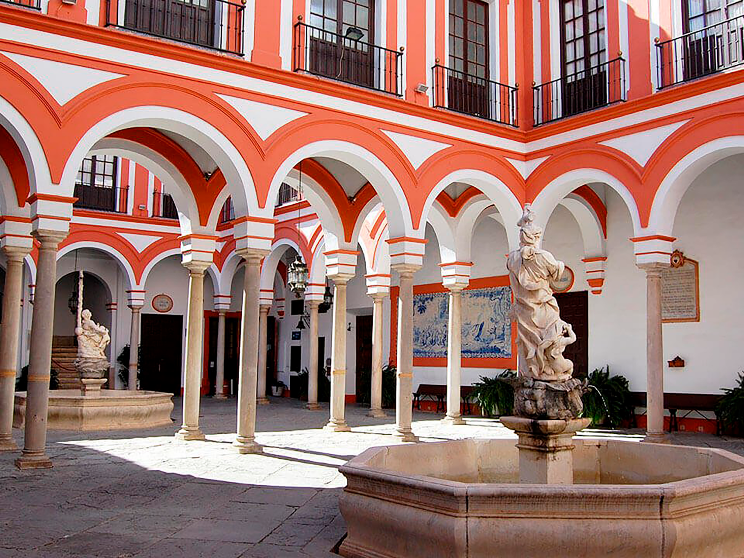 Arcadas del Hospital de la Caridad en Sevilla con una fuente en primer plano y otra al fondo, visita cultural con Conoce Sevilla
